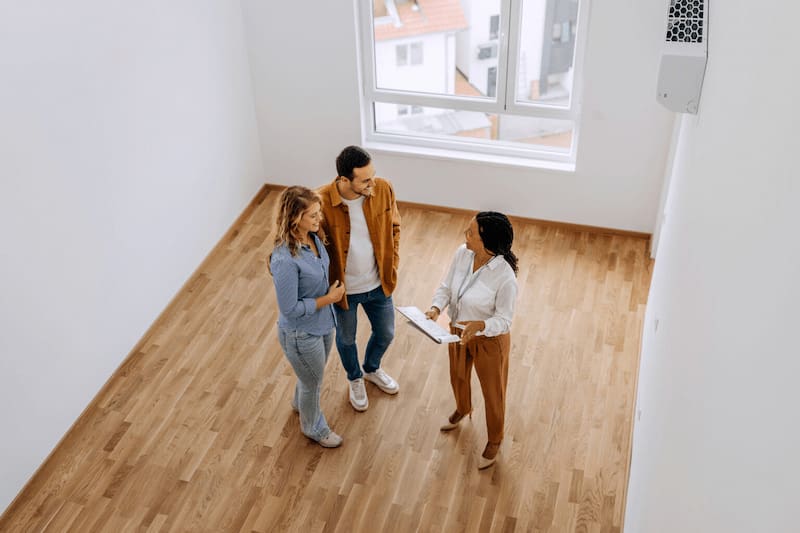High Angle View Of Real Estate Agent Talking With Young Couple At Empty Apartment